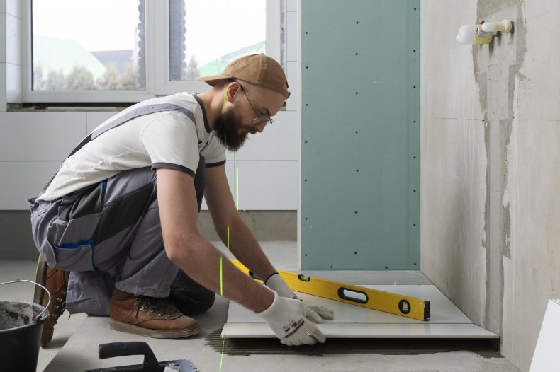 Instalator montuje system ogrzewania podłogowego w remontowanej łazience