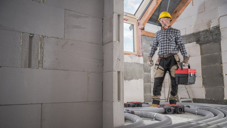 Instalator na poddaszu montuje system domu pasywnego z rekuperacją
