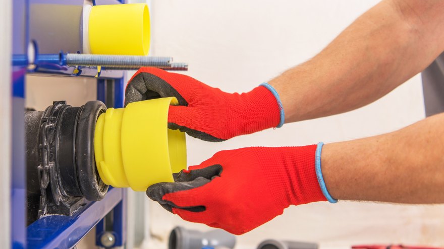 Instalator montuje ujście kanalizacji wewnętrznej grawitacyjnej w stelażu