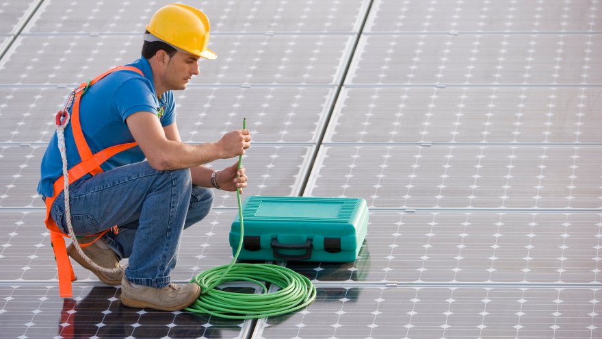 Instalator podłącza panele fotowoltaiczne kablem solarnym