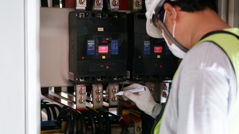 Elektroinstalator przy rozdzielnicy elektrycznej sprawdza działanie zasilacza UPS