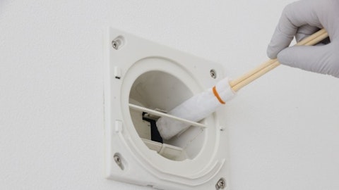 Instalator czyści czerpnie powietrza wacikiem na patyku w pokoju