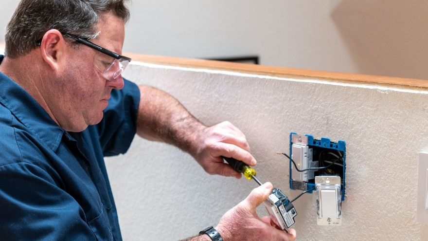 Instalator montuje włącznik światła krzyżowo w mieszkaniu