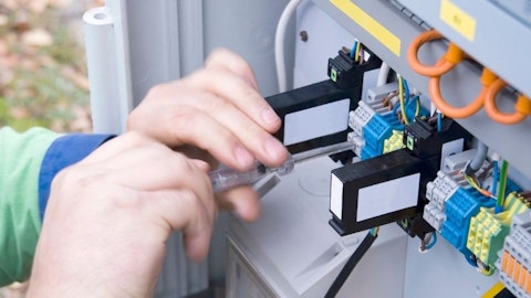 Instalator montuje aparaturę elektryczną w rozdzielnicy zewnętrznej na ogródku
