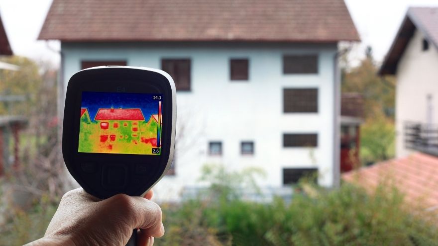 Elektromonter sprawdza efektywność cieplną budynku pirometrem na kamerze termowizyjnej