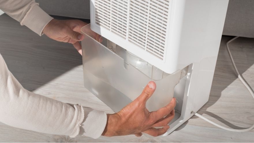 Instalator wymienia pojemnik z wodą w osusaczy powietrza w salonie