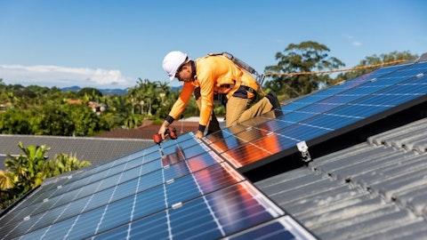 Instalator montuje panele solarne na dachu pochyłym