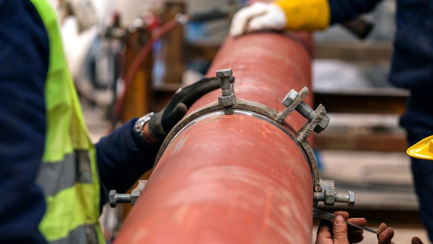 Instalatorzy nakładają opaskę nawiercającą na rury kanalizacyjne