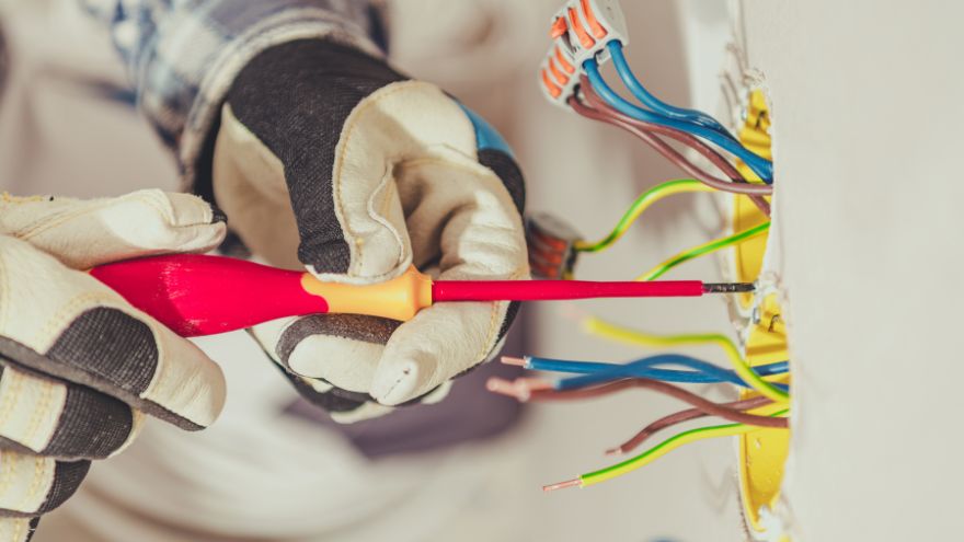Instalator montuje puszki elektryczne w ścianie pod obwody elektryczne