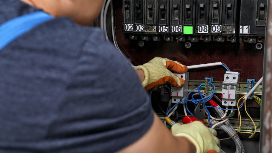 Elektrotechnik łączy aluminiowe przewody instalacyjne w rozdzielnicy elektrycznej