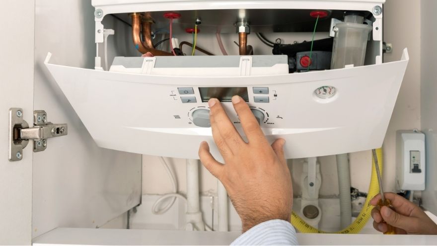 Instalator montuje piec gazowy do szafy w kuchni