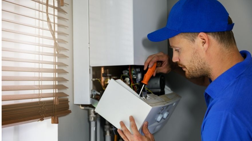 Instalator sprawdza jak odpowietrzyć piec gazowy na ścianie w kuchni