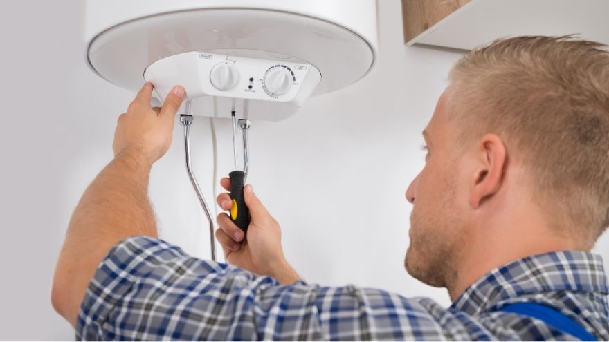 Instalator odkręca spód bojlera w łazience chcąc opróżnić bojler