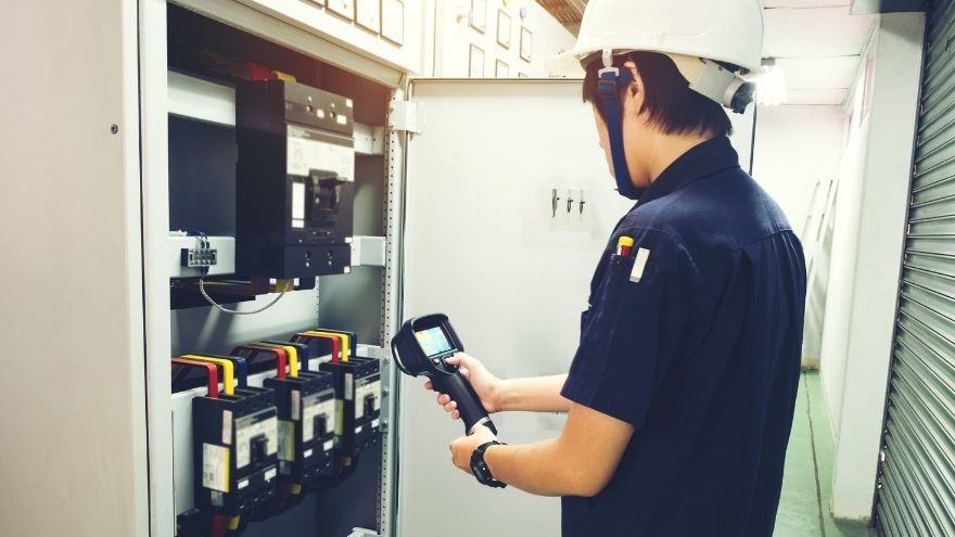Młody Instalator sprawdza sprawność elektryczną szafy rozdzielczej kamerą termowizyjną
