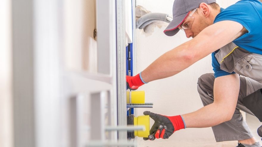 Instalator montuje w łazience miskę podtynkową na stelażu