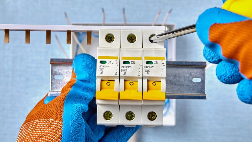 Elektryk montuje wyłącznik różnicowo-prądowy na szynie do rozdzielnicy