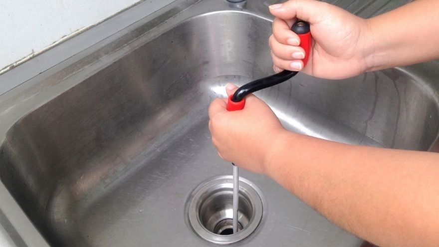 Instalator czyści instalacje hydrauliczna w zlewie spiralą do rur