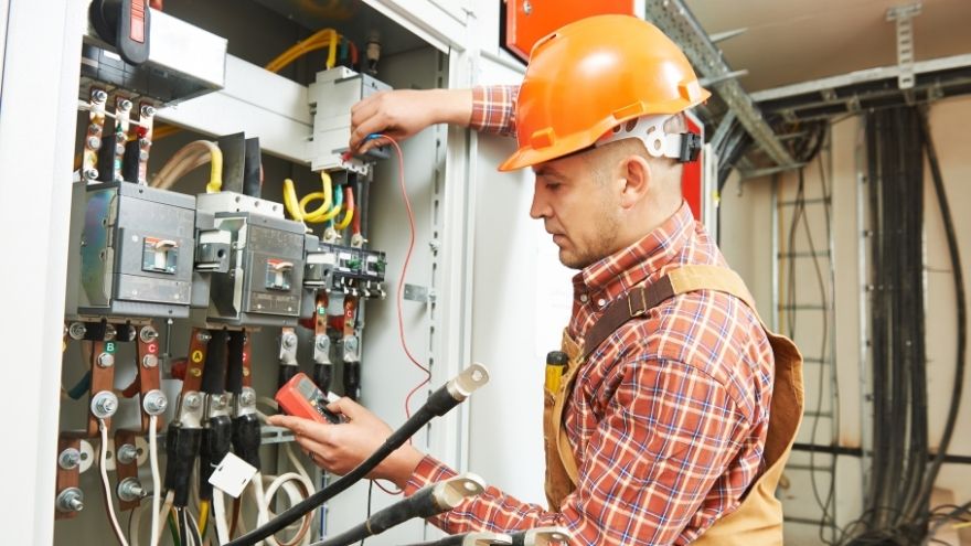 Elektryk sprawdza działanie instalacji elektrycznej przy rozdzielnicy wewnętrznej