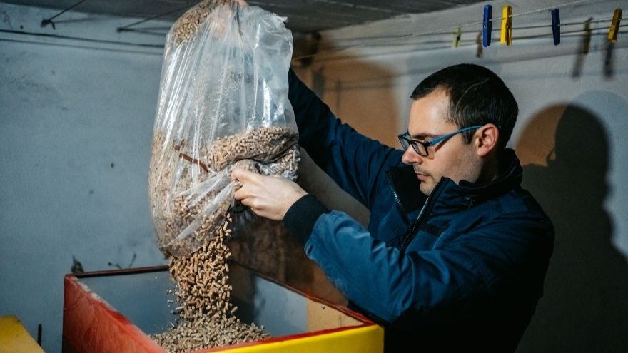 Instalator napełnia pelletem kocioł przy pierwszym uruchomieniu w kotłowni