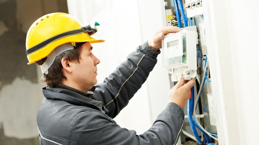 Elektryk podłącza licznik energii elektrycznej do instalacji kabli i przewodów