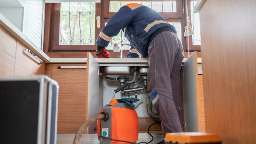 Instalator udrażnia kanalizację metodą ciśnieniową w kuchni