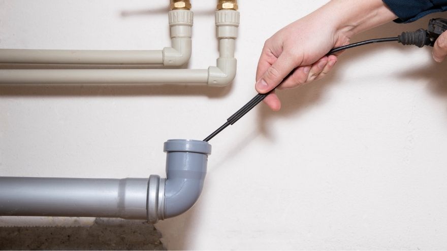 Instalator czyści rurę kanalizacyjną tworzywową