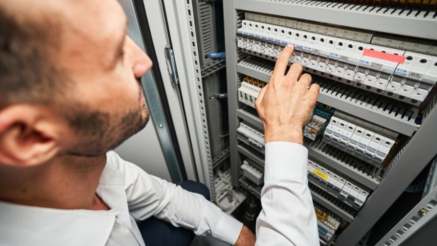 Elektryk wtącza obwód elektryczny zasilacza impulsowego przy szafie rozdzielczej