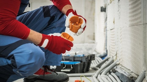 Instalator w pomieszczeniu w stanie surowym podłącza kable elektryczne do obwodów z puszką instalacyjną