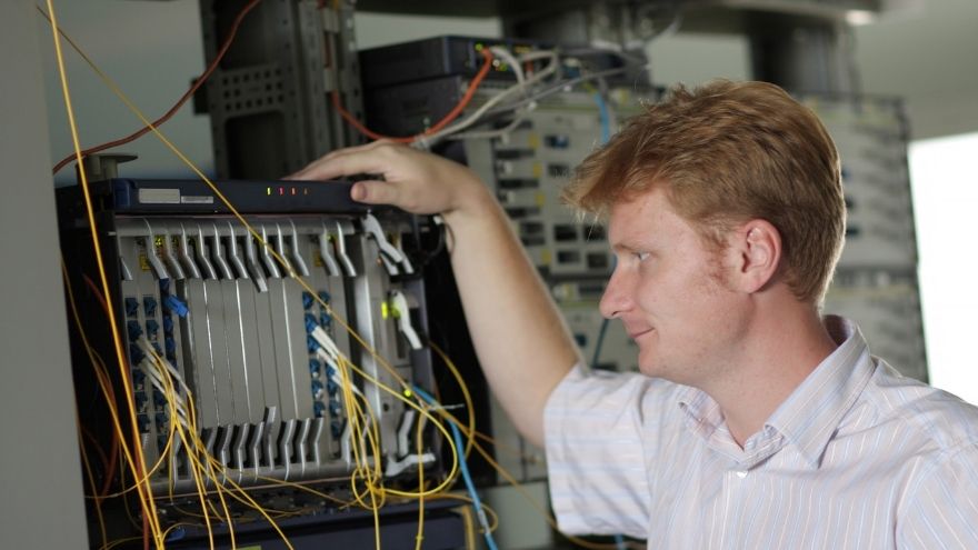 Technik informatyk sprawdza podłączenie do sieci multipleksera w rozdzielnicy IT