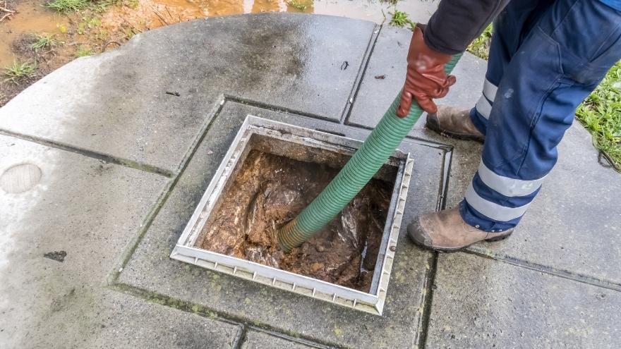 Szambiarz oczyszcza szambo betonowe na działce domu jednorodzinnego