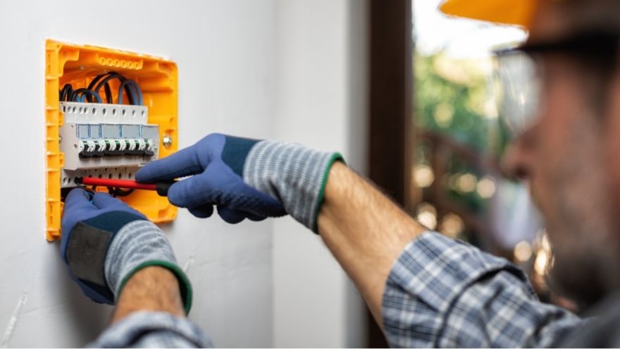 Монтажник встановлює електрообладнання та запобіжники в електрощиті для захисту від перенапруги. Instalator montuje aparaturę elektryczną i bezpieczniki w rozdzielnicy elektrycznej dla ochrony przepięciowej