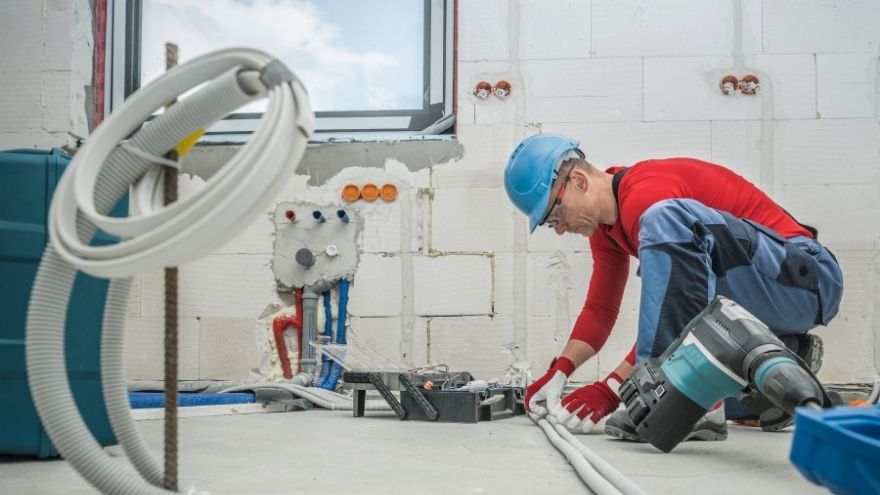 Elektryk montuje instalację elektryczną z bruzdami na ścianie pod kable i przewody