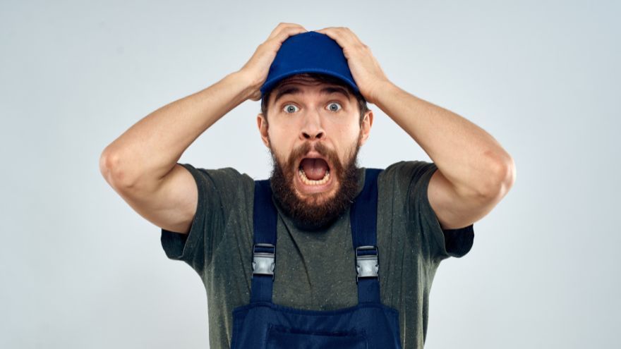 Instalator, hydraulik krzyczy na szarym tle zszokowany