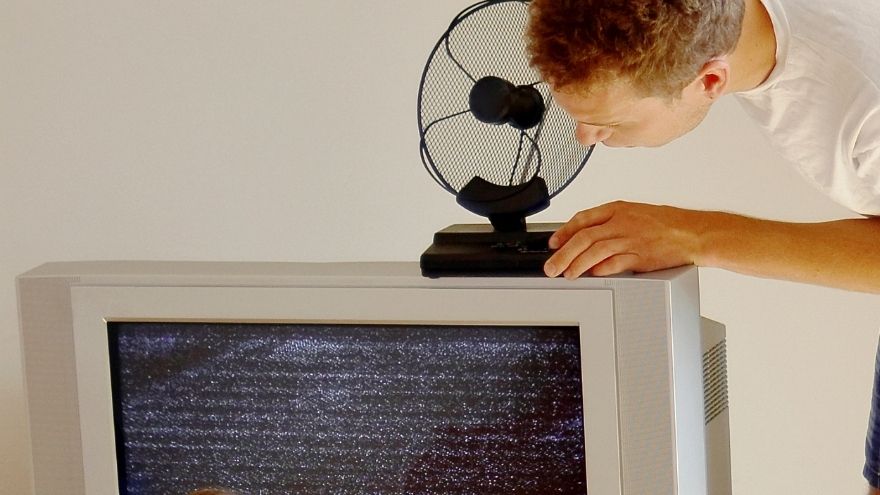 Domownik ustawia antenę wewnętrzną na telewizorze w salonie