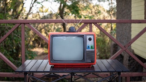 Telewizor turystyczny na stoliku na werandzie przed domem jednorodzinnym z anteną