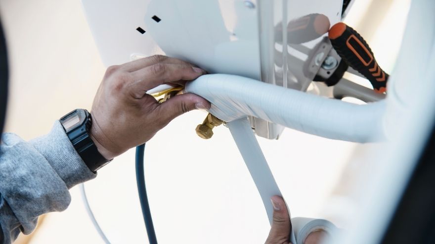 Instalator montuje jednostkę zewnętrzną klimatyzacji na stelażu podwieszanym