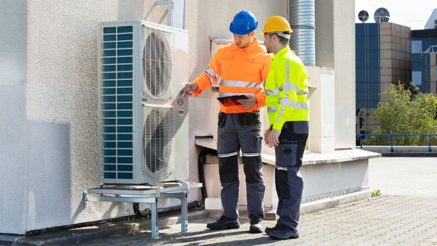 Technicy inżynierowie sprawdzają działanie jednostki zewnętrznej klimatyzacji budynku