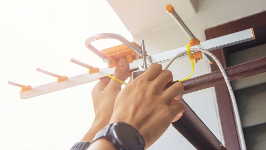 Technik elektryk ustawia antenę zewnętrzną na sygnał telewizyjny