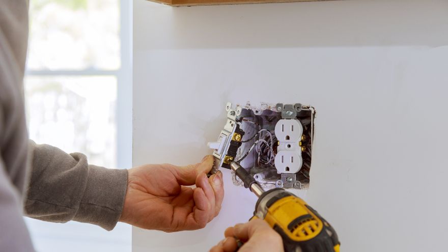 Elektryk instaluje gniazdko elektryczne w ścianie