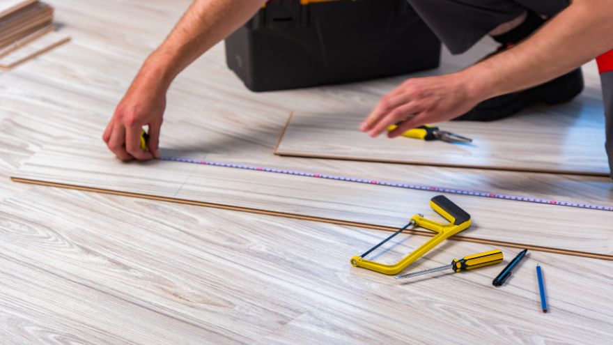 A professional installer lays wooden panels in the living room of an apartment Profesjonalny montażysta układa panele drewniane w salonie mieszkania