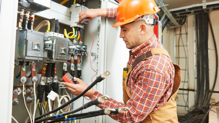 Instalator sprawdza napięcie w rozdzielni elektrycznej