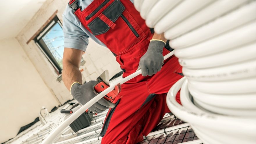 Instalator montuje system ogrzewania podłogowego w mieszkaniu