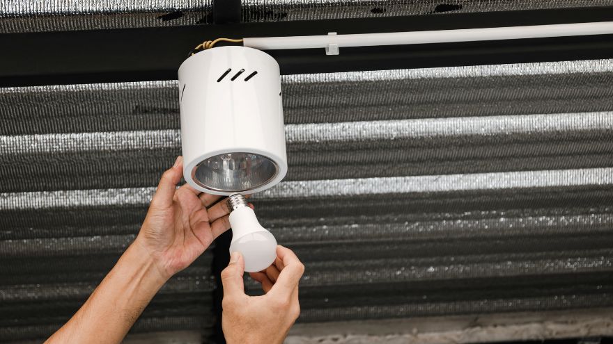 Instalator wkręca żarówkę LED oświetleniową pomieszczenia do lampy