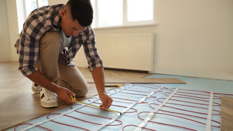 Instalator mierzy instalację ogrzewania podłogowego elektrycznego w mieszkaniu