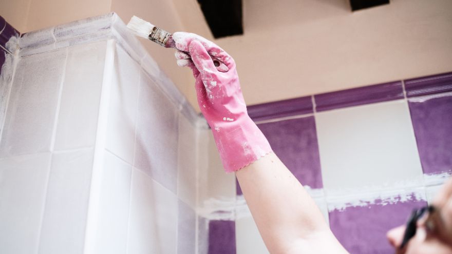 Pracownik budowlany maluje płytki w łazience na biało