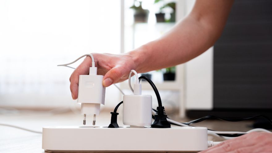 Domownik odłącza urządzenia elektryczne od przedłużacza, aby oszczędzić