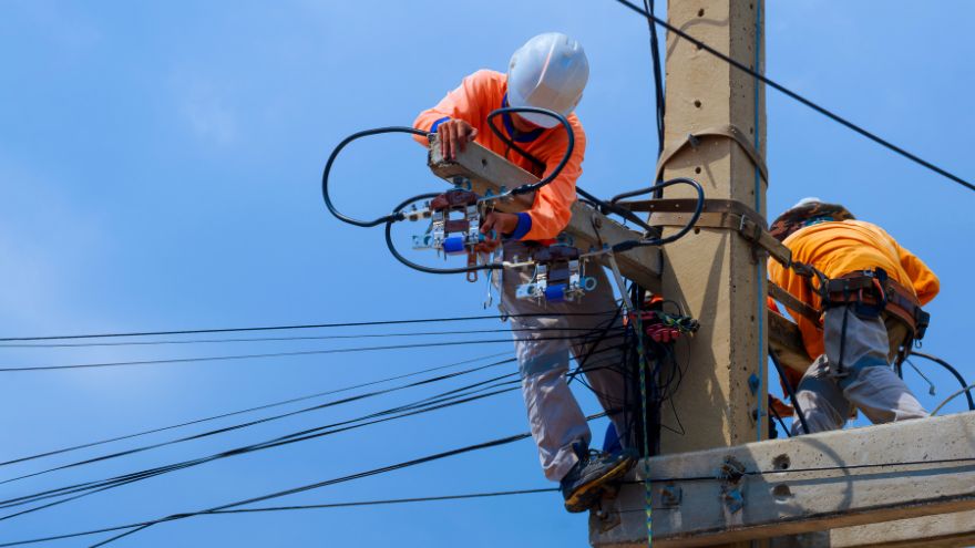 Elektrycy wysokich napięć na słupie elektrycznym