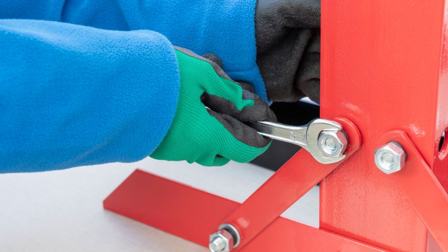 Instalator dokręca śruby w stelażu stalowym kluczem płaskim