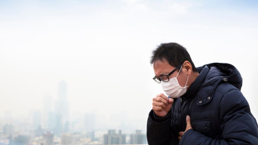 Чоловік у масці на тлі смогу