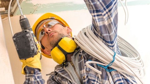 Instalator montujący kable z wiertarką w ręku